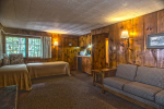 Wood paneled room with 2 beds and couch
