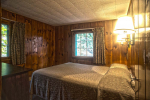 Wood panel bedroom with white blanket on bed